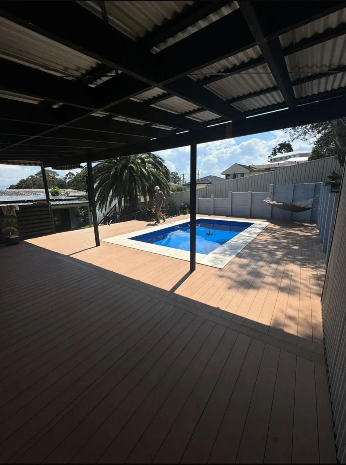 Large composite deck wrapping a pool under a pitched patio cover
